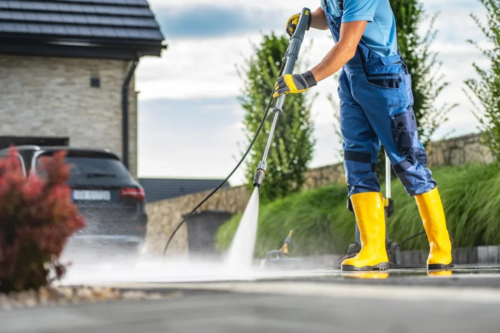 Worker pressure washing outdoor sidewalk in residential/commercial setting